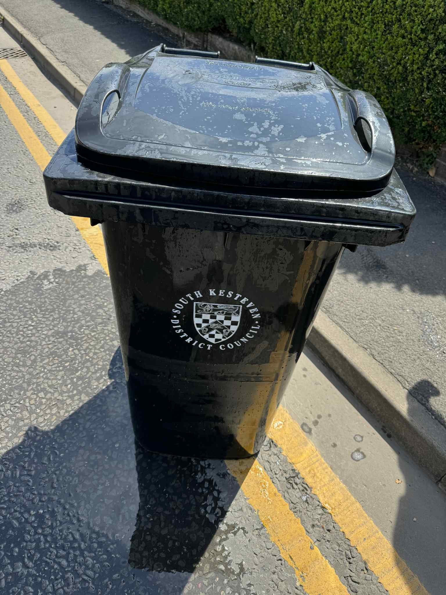 A clean black wheelie bin